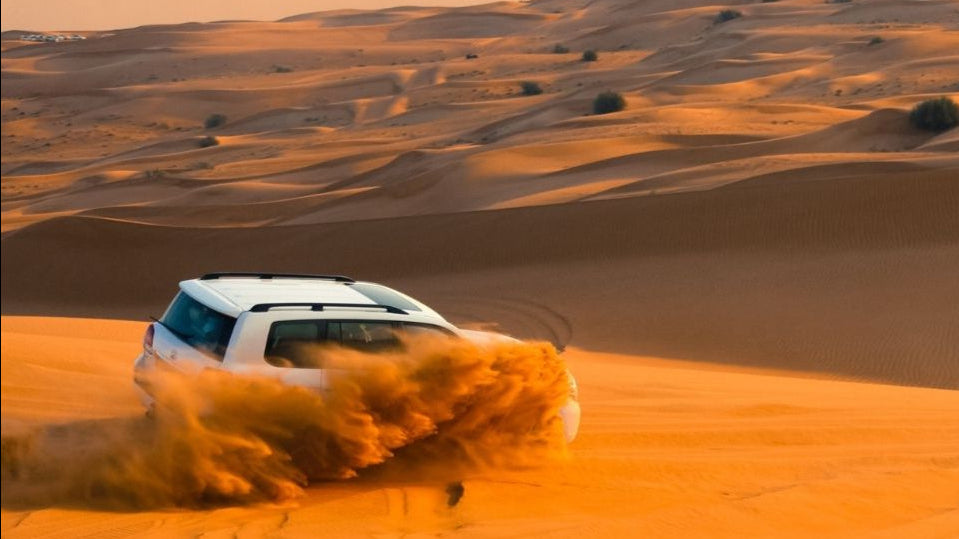 Off-road vehicle driving through sand dunes in a desert landscape