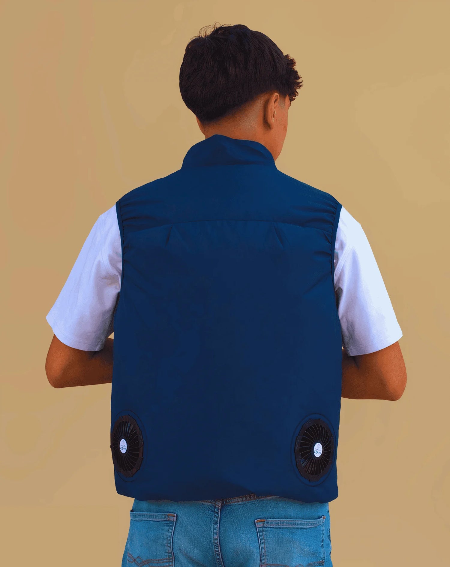 Person wearing a blue cooling vest with two black fans showing from the backside on a beige background