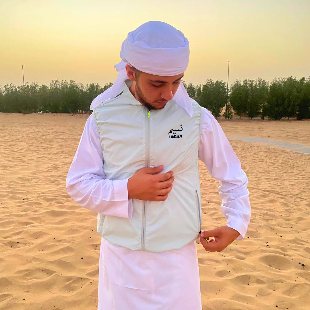 Person wearing a white outfit and Naseem white cooling vest with a headscarf in a desert setting